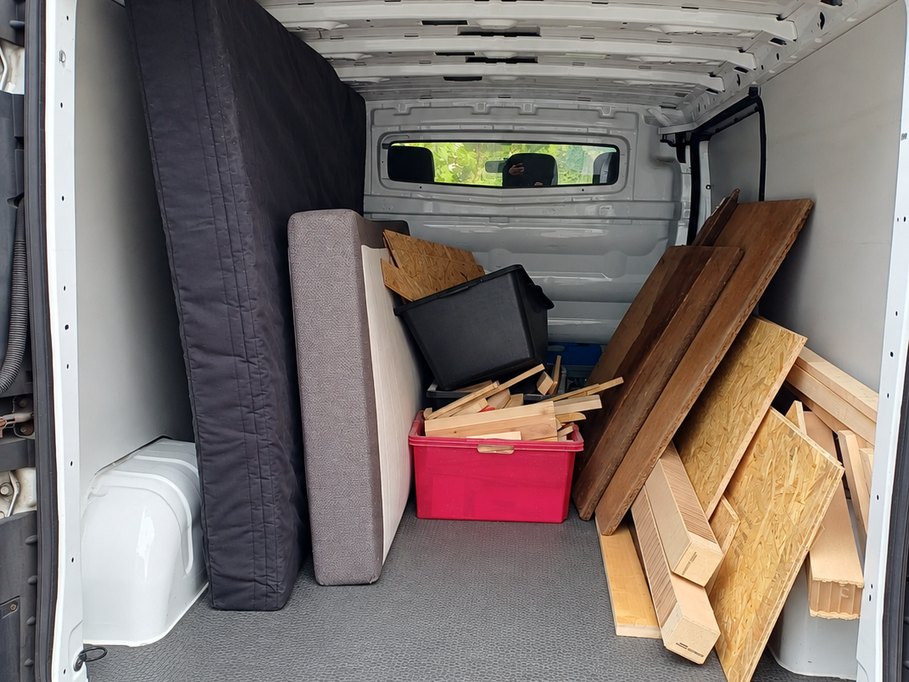 Blick in den beladenen Laderaum eines Transporters mit Matratzen, Kisten und Holzplatten