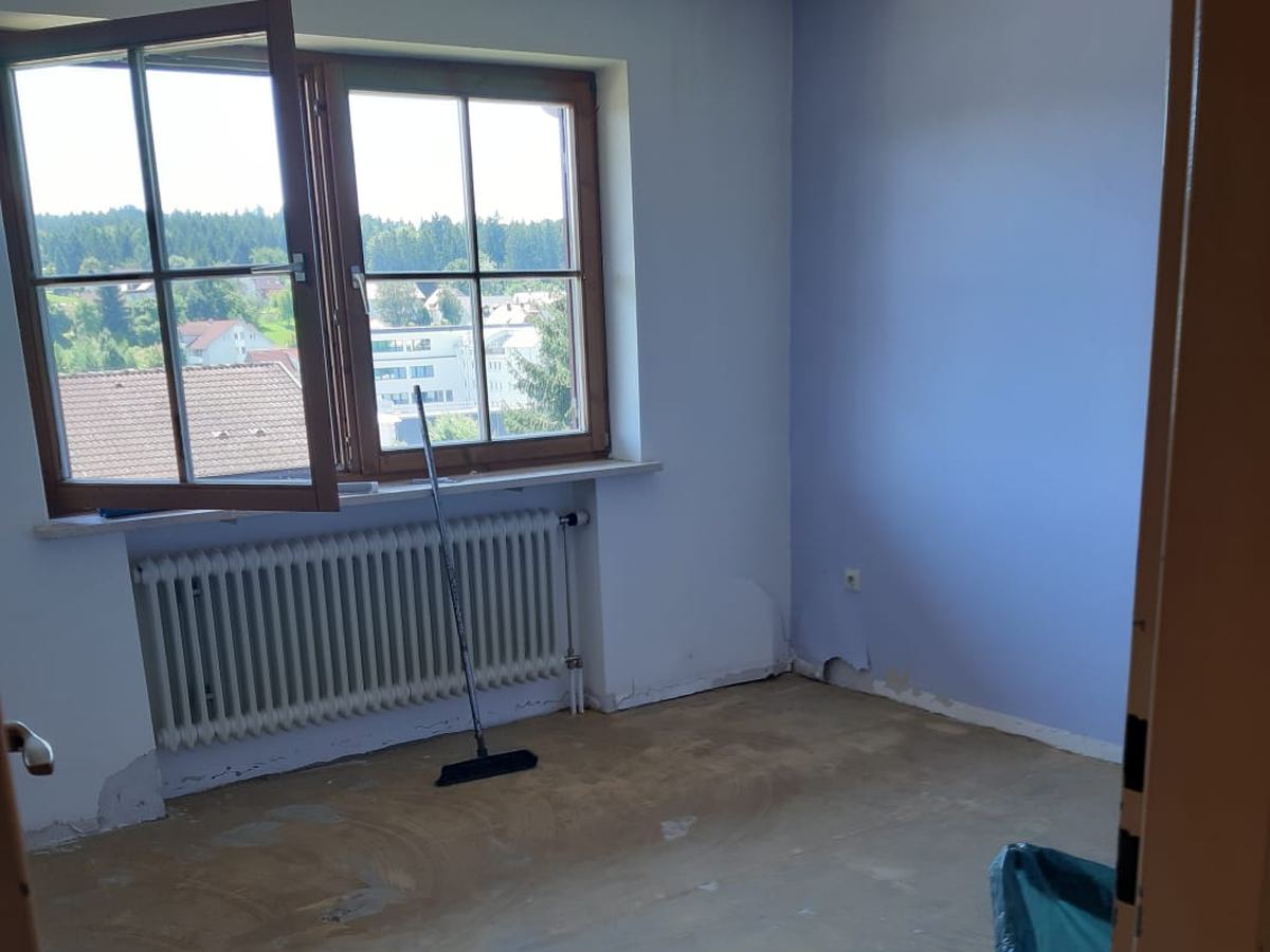 Leer geräumtes Zimmer mit offenem Fenster, Heizkörper und besenrein gekehrtem Boden